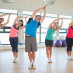 Fitness class and instructor standing in Namaste position at exercise studio